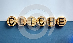 Word `CLICHE` on wood circles, beautiful white and blue background. Business concept. Copy space