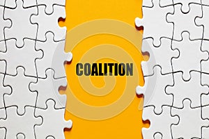 The word coalition between the jigsaw puzzle pieces. Alliance, cooperation and collaboration in business or politics