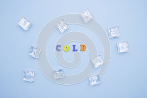 The word COLD on a blue background of wooden multicolored letters, ice cubes around the word