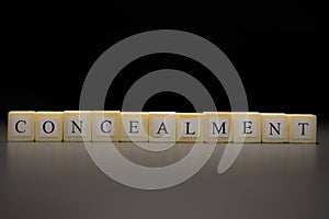 The word CONCEALMENT written on wooden cubes isolated on a black background