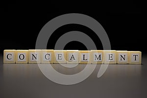 The word CONCEALMENT written on wooden cubes isolated on a black background photo