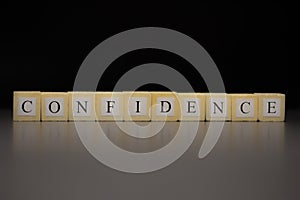 The word CONFIDENCEwritten on wooden cubes isolated on a black background