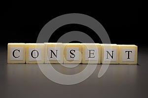 The word CONSENT written on wooden cubes isolated on a black background