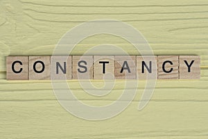 the word constancy of gray small wooden letters photo