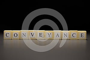 The word CONVEYANCE written on wooden cubes isolated on a black background