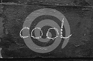 The word cool written with chalk on black stone.