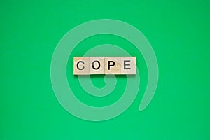Word cope. Top view of wooden blocks with letters on green surface