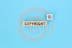The word copyright and copyright symbol on wooden blocks on Blue background. Concept of patenting or copyright protection