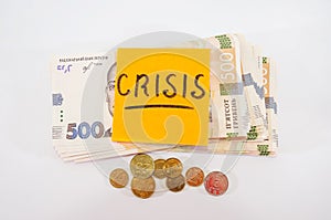 The word `crisis` on the sticker and 500 hryvnia, white background. Business concept Economic crisis concept.