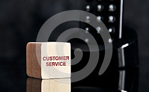 The word customer service on wooden block with telephone background. Business concept for support or technical help