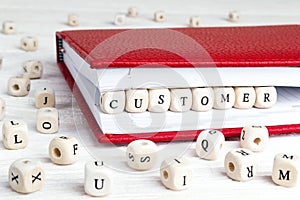 Word Customer written in wooden blocks in red notebook on white