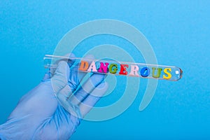 Word dangerous in test-tube holding a gloved hand