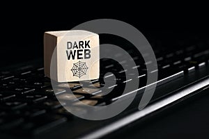 The word dark web on wooden cube with computer keyboard. Cyber crime and illegal outlets in cyberspace or internet technology