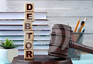 The word DEBTOR on wooden cubes against the background of the judge\'s gavel and stand