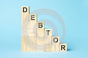 the word DEBTOR is written on a wooden cubes, concept