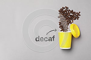 Word Decaf and arrow pointing at takeaway paper cup with coffee beans on light grey background, flat lay. Space for text