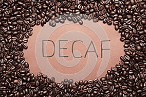 Word Decaf and coffee beans on brown background, top view