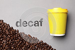 Word Decaf, coffee beans and takeaway paper cup on light grey background, flat lay