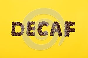 Word Decaf made of coffee beans on yellow background, flat lay