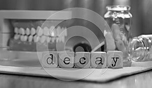 Word DECAY composed of wooden dices. Pills, documents, pen, human jaw model in the background