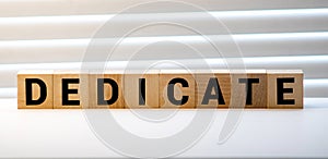 Word Dedicate on a row of wooden blocks. Devotion dedication love concept
