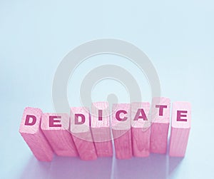 Word Dedicate on a row of wooden blocks. Devotion dedication love concept