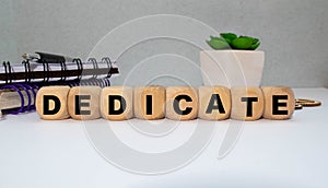 Word Dedicate on a row of wooden blocks. Devotion dedication love concept.