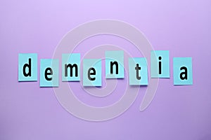 Word Dementia made of paper notes on violet background, flat lay