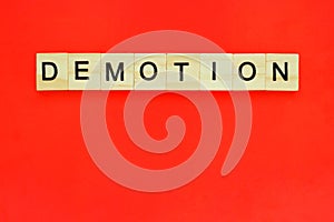 Word demotion. Top view of wooden blocks with letters on red surface