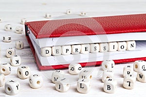 Word Depression written in wooden blocks in red notebook on whit