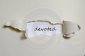 The word devoted appearing behind torn paper