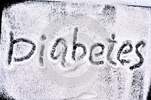 The word diabetes is written on a black chalkboard with a bunch of sugar