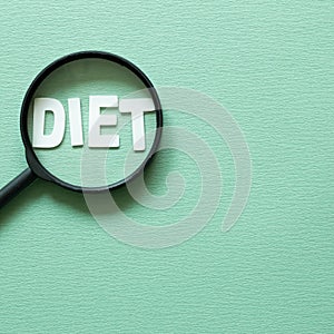 Word `Diet` and magnifying glass on green background