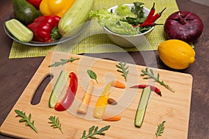 Word Diet written with different raw vegetables, fruits and greens on wooden cutting board. Organic ingredients for diet food