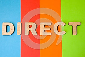 Word Direct of large wooden letters on colored background of 4 colors: blue, orange, red and green. Photo or symbol of the directi