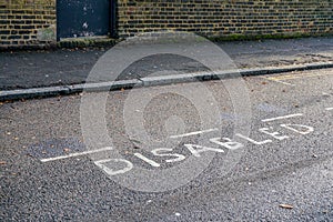 Word DISABLED written on asphalt near reserved parking space at street in outer London