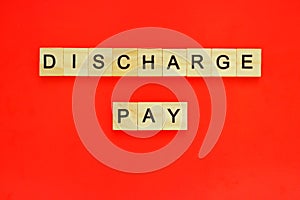 Word discharge pay. Top view of wooden blocks with letters on red surface