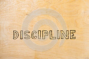 Word discipline handwritten with woodburner on flat wooden surface - directly above normal view