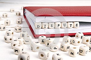 Word Dispute written in wooden blocks in red notebook on white w photo