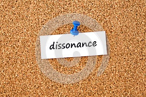 Word dissonance written on a piece of paper, cork board background