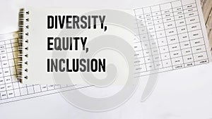 The word Diversity, Equity and Inclusion on a notepad with papers and numbers on a wooden background. DEI concept for business.