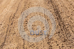 The word dust standing on dusty road surface in linear perspective