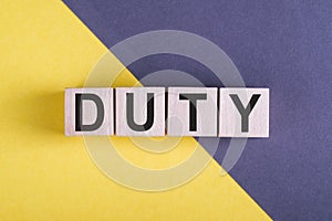 Word DUTY on wooden cubes on yellow - gray background