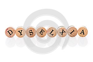 Word Dyslexia intentionally misspelled from circular wooden tiles with letters children toy. Concept of learning difficulty