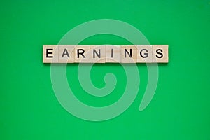 Word earnings. Top view of wooden blocks with letters on green surface