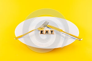Word 'eat' on wooden blocks on a plate