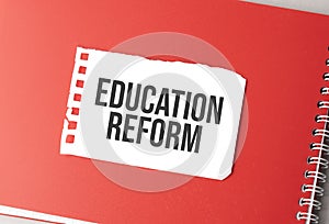 The word Education Reform on torn paper on red notepad