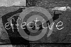The word EFFECTIVE written with chalk on black stone with man shadow on it