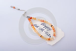 the word EID EL FITR   on torn paper beside prying beads