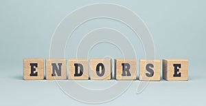 The word ENDORSE made from wooden cubes on blue background